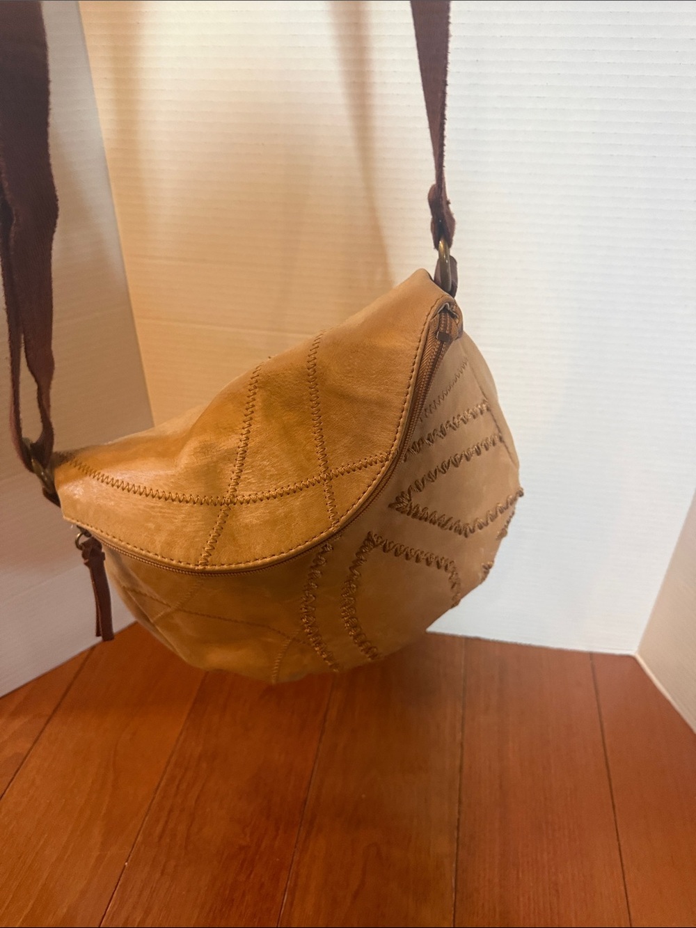 The Sak Deena fold-over crescent crossbody bag. tan leather peace sign stitch